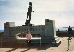 Photograph of a woman standing in front of a monument to Canadian Terry Fox. 